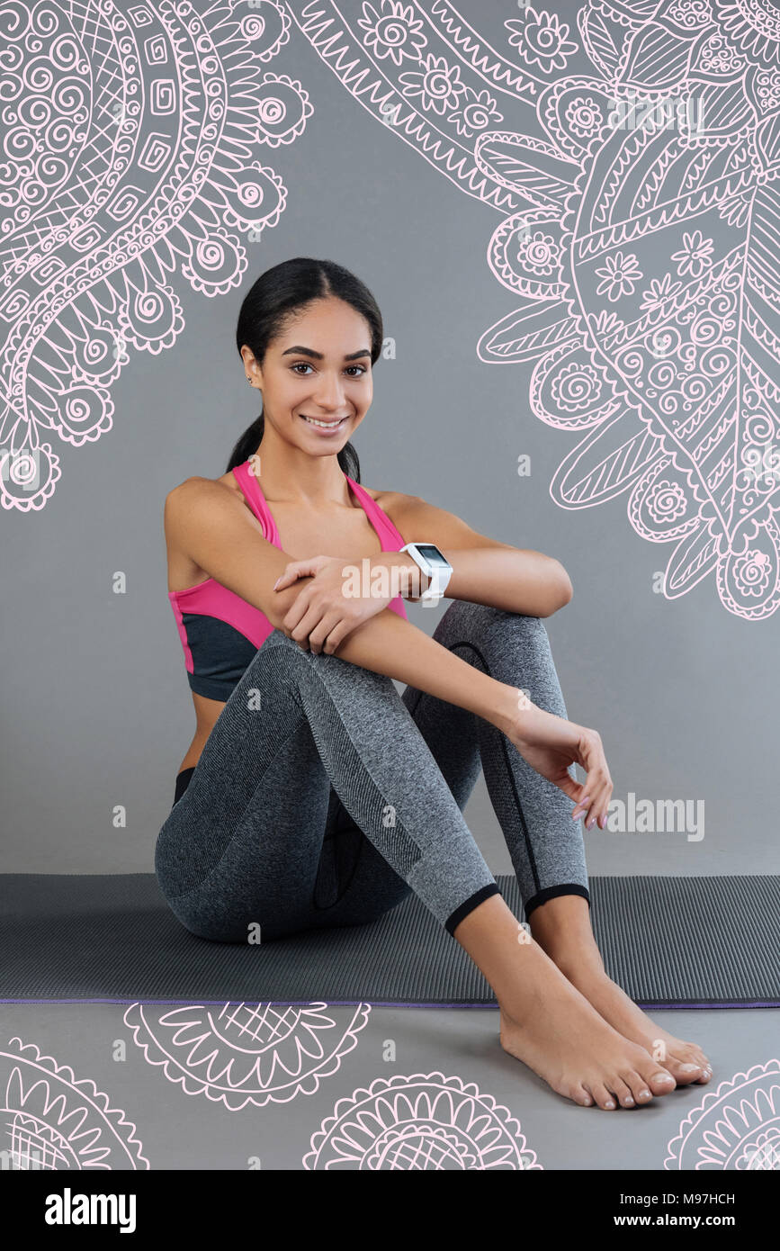 Cute Sport Trainer lächelnd und sitzt auf einem Yoga Matte Stockfoto
