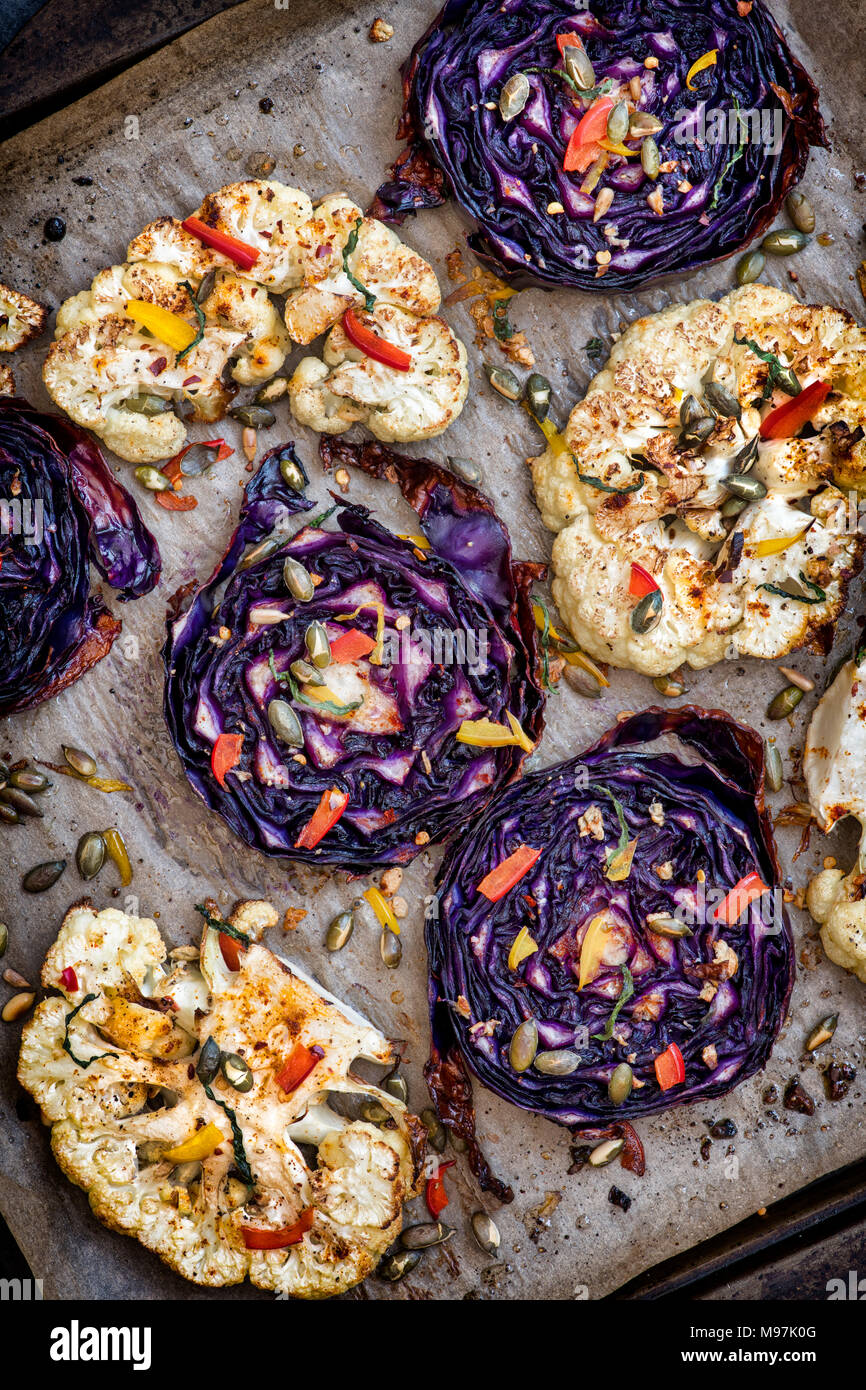 Gebratener Rotkohl und Blumenkohl Steaks mit Samen, gehackt Pfeffer, Knoblauch, Minze und Gewürzen. Großbritannien Stockfoto