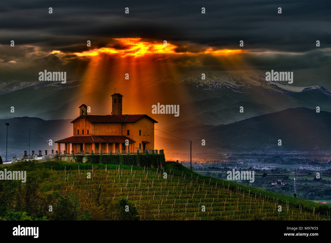 Ein Lichtstrahl durch die stürmischen Wolken und scheint auf die Kapelle des Partisanen Schrein von Bastia Mondovì, Langhe, Piemont, Italien. Stockfoto