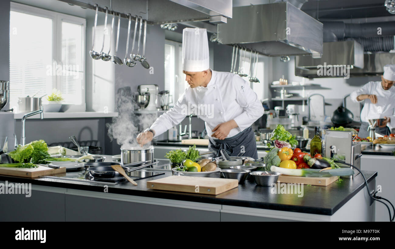 Dem berühmten Küchenchef arbeitet in einem großen Restaurant Küche mit seinen Auszubildenden. Küche ist voller Essen, Gemüse und kochende Gerichte. Stockfoto