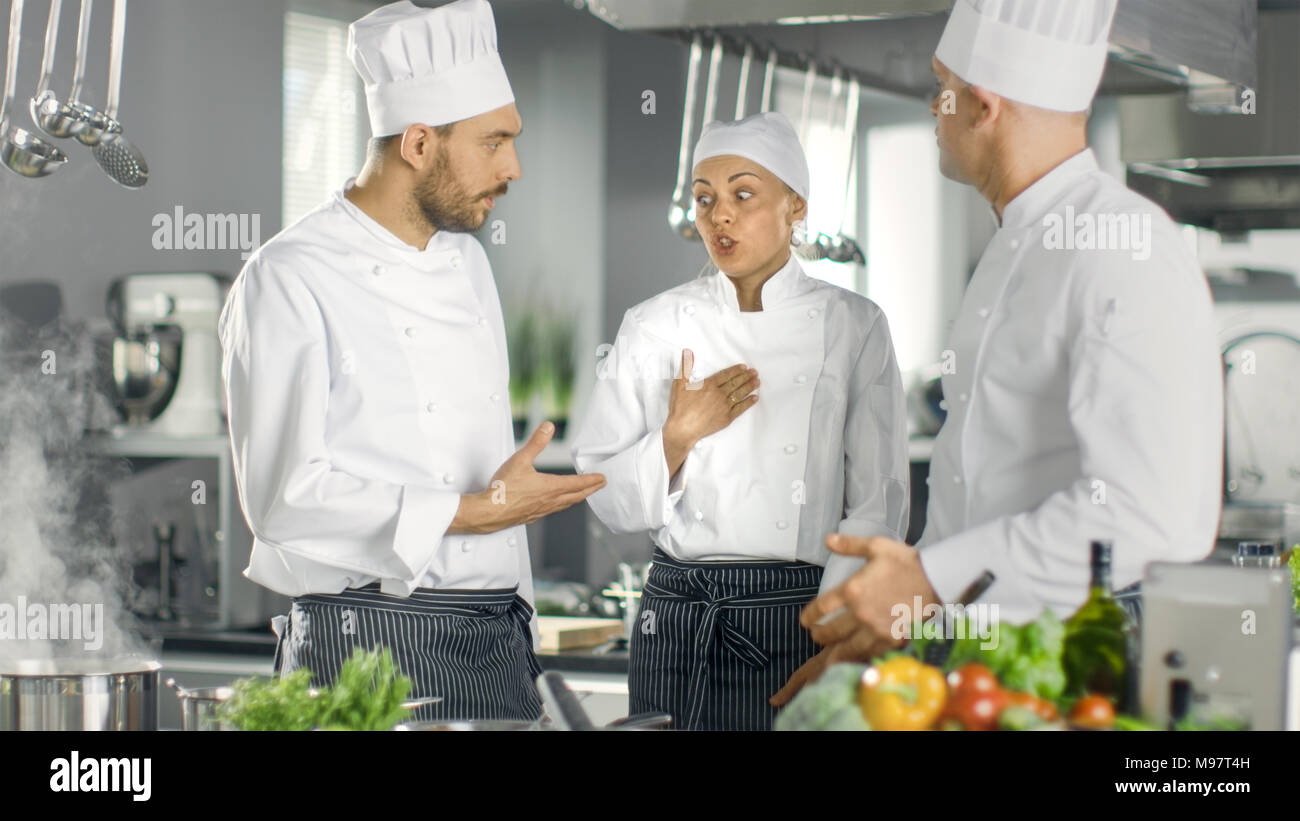 In der modernen Küche Team von Köchen, Diskussion. Küche ist voll von Lebensmittelzutaten, Gemüse, Fleisch, kochende Suppe. Stockfoto