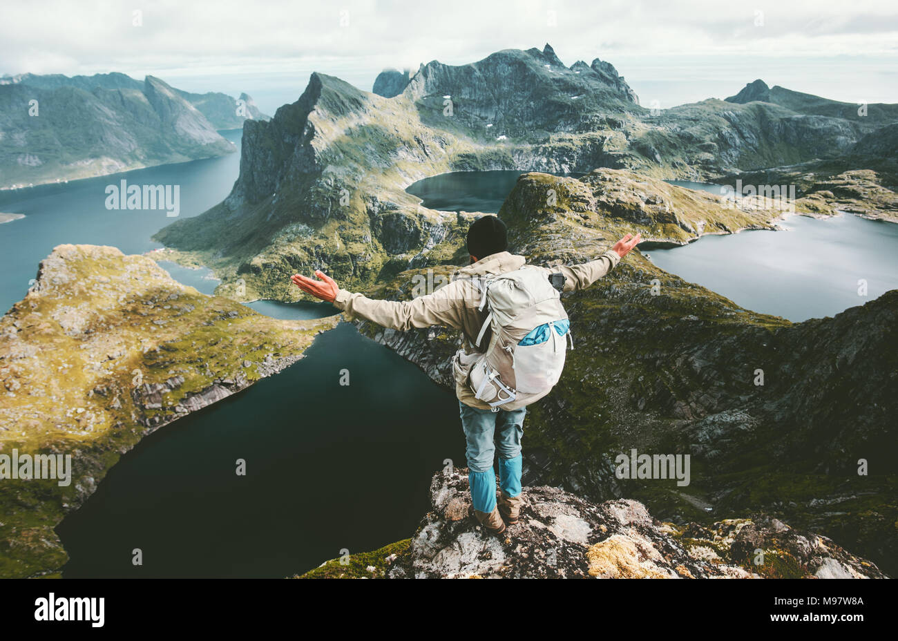 Backpacker Mann erhobenen Hände auf Hermannsdalstinden Berg in Norwegen Reisen lifestyle Abenteuer Konzept Wandern Sommer aktiv Urlaub im Freien Stockfoto