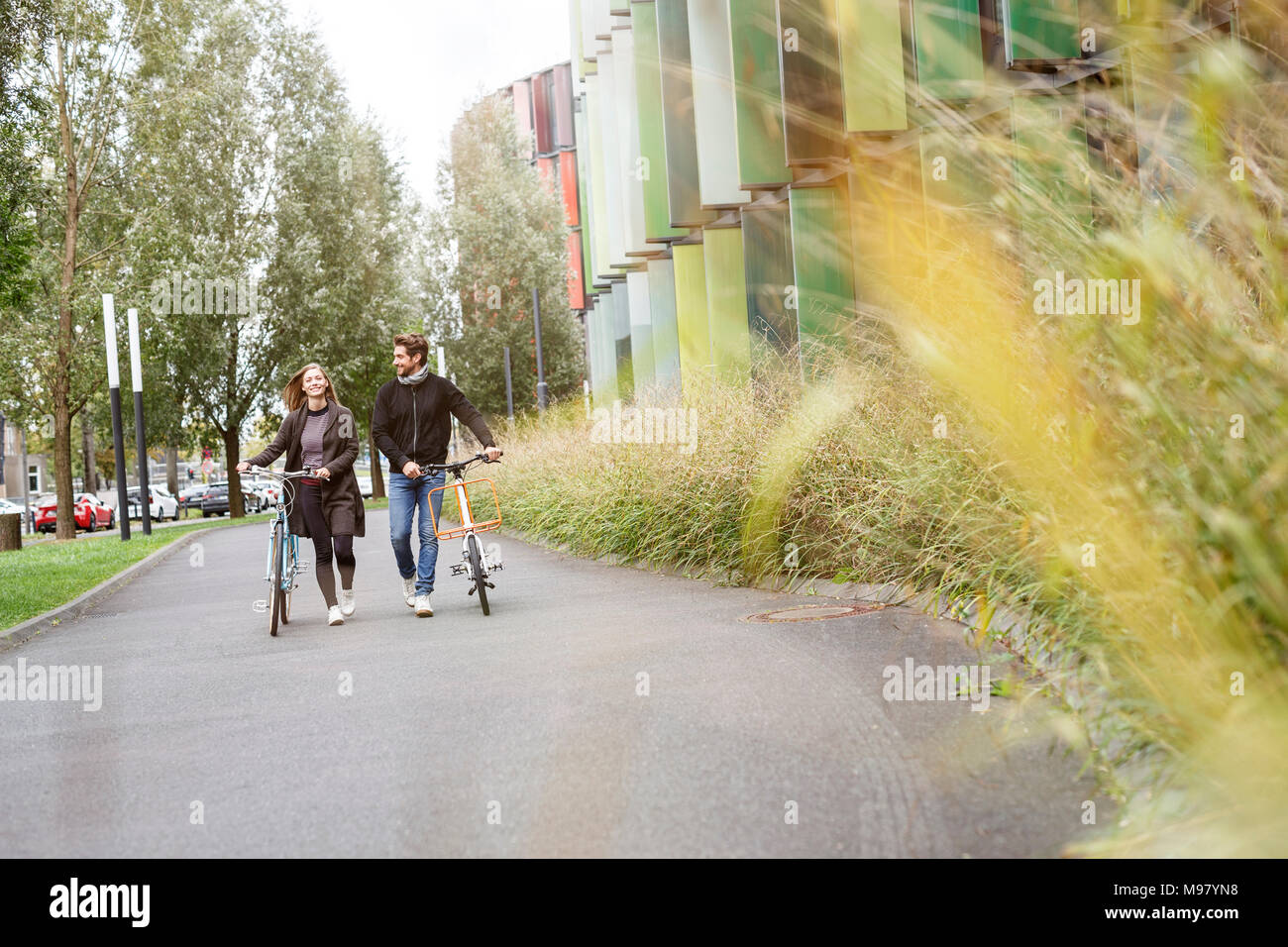 Lächelndes Paar zu Fuß mit dem Fahrrad auf der Spur Stockfoto