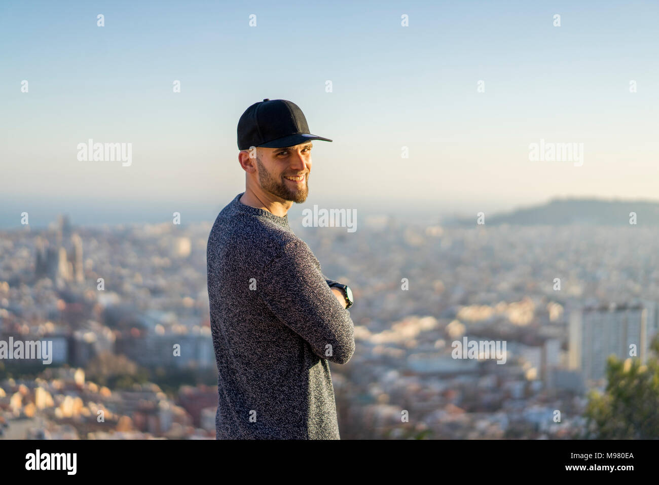 Spanien, Barcelona, lächelnden jungen Mann, der auf einem Hügel mit Blick auf die Stadt Stockfoto