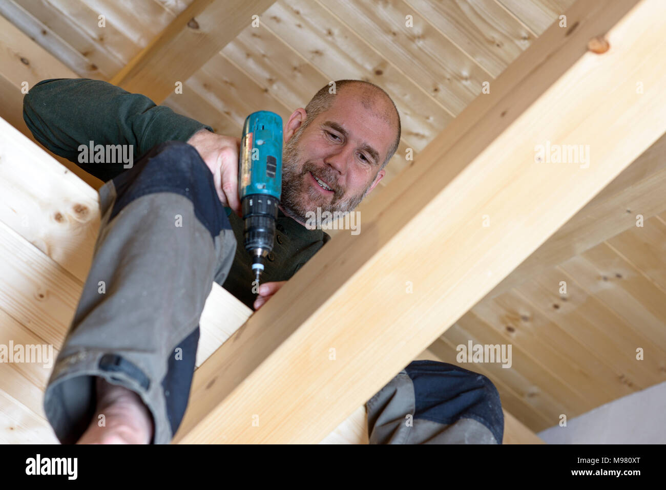 Mann mit Bohrer, Innenausbau Obergeschoss, Boden legen, Holzhaus, Bayern, Deutschlaned Stockfoto