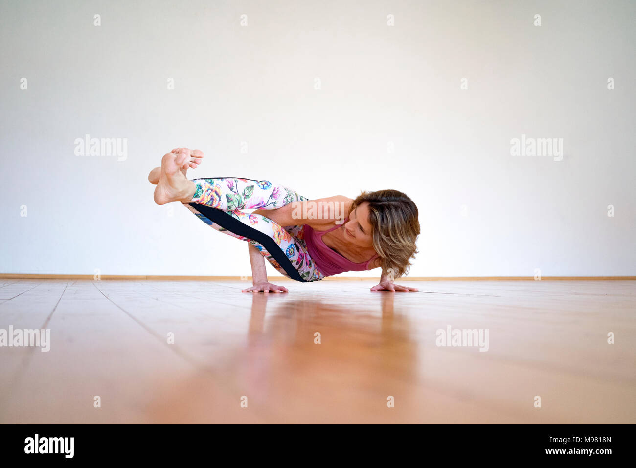 Reife frau yoga auf Fußboden im leeren Raum Stockfoto