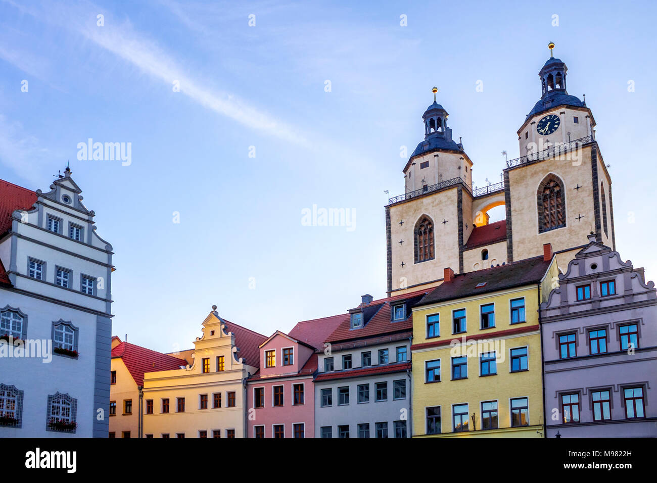 Deutschland, Lutherstadt Wittenberg, Blick auf Rathaus, Reihe von Häusern und der Kirche St. Mary im Hintergrund Stockfoto