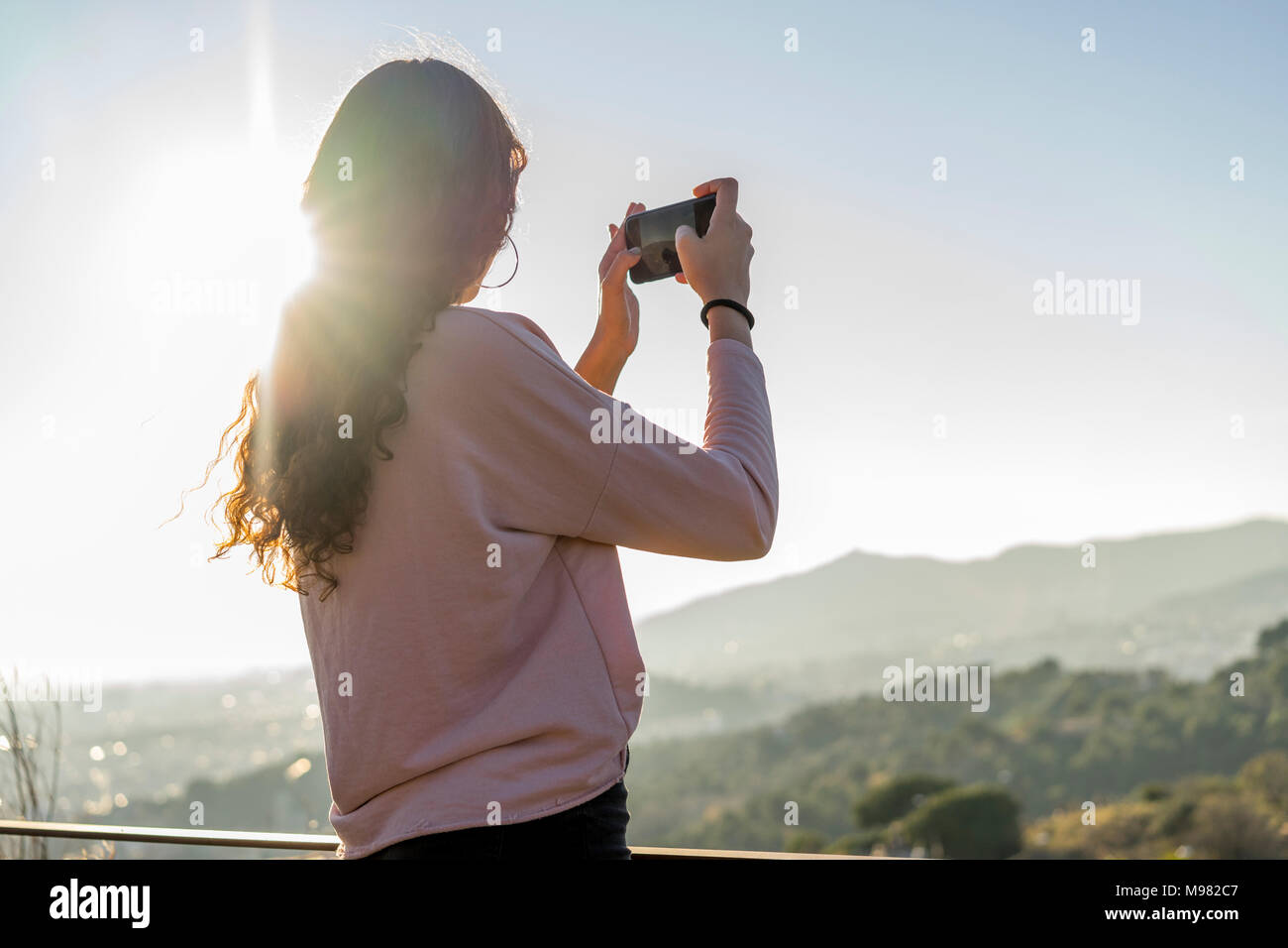 Junge Frau auf einem Hügel unter Handy Bild Stockfoto