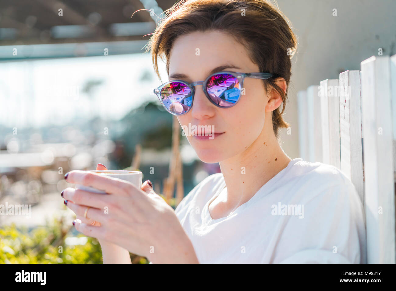 Portrait von Frau mit Tasse Kaffee mit verspiegelten Sonnenbrillen. Stockfoto