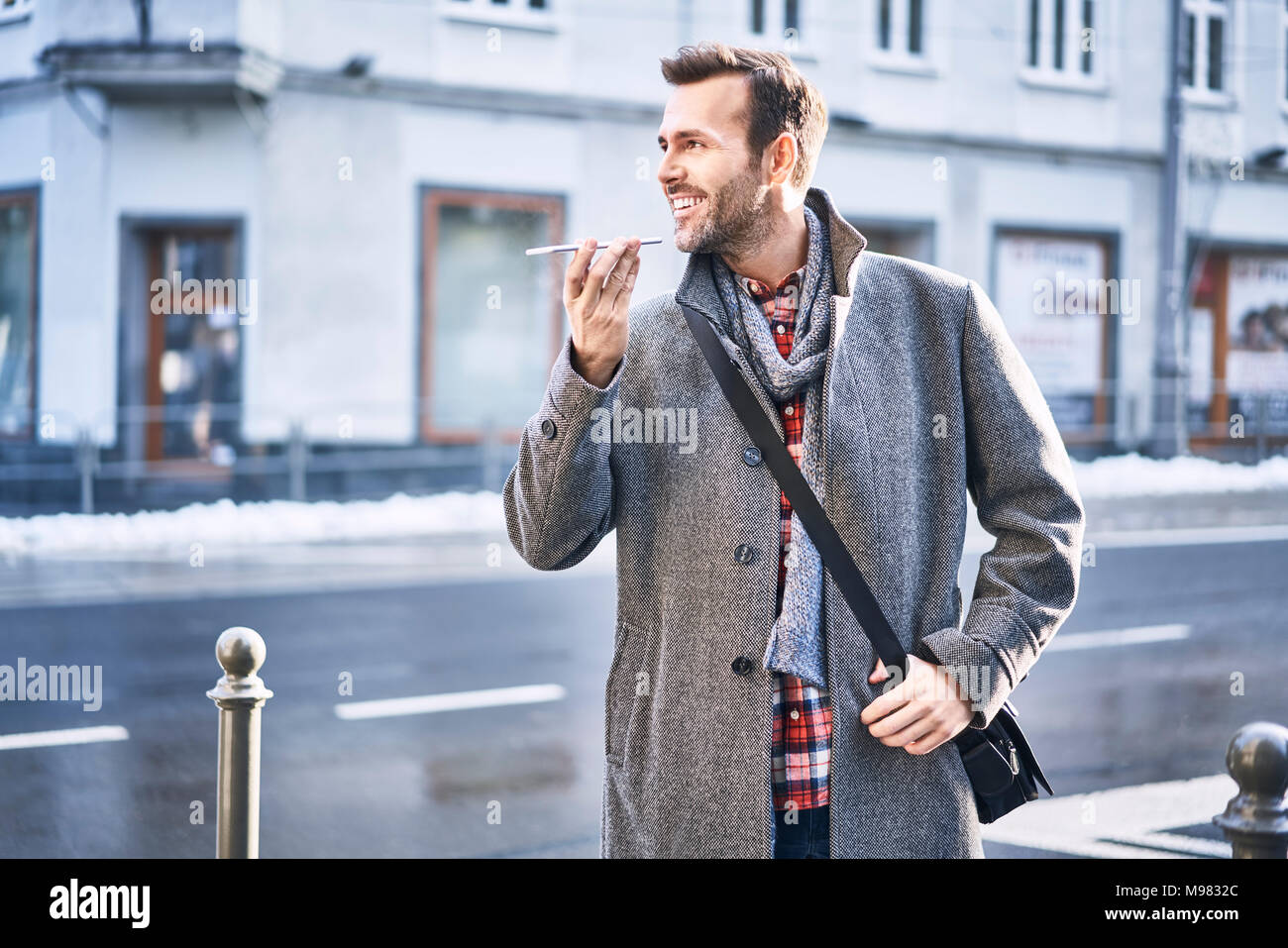 Der Mensch am Telefon zu sprechen auf die Straße der Stadt während der sonnigen Wintertag Stockfoto