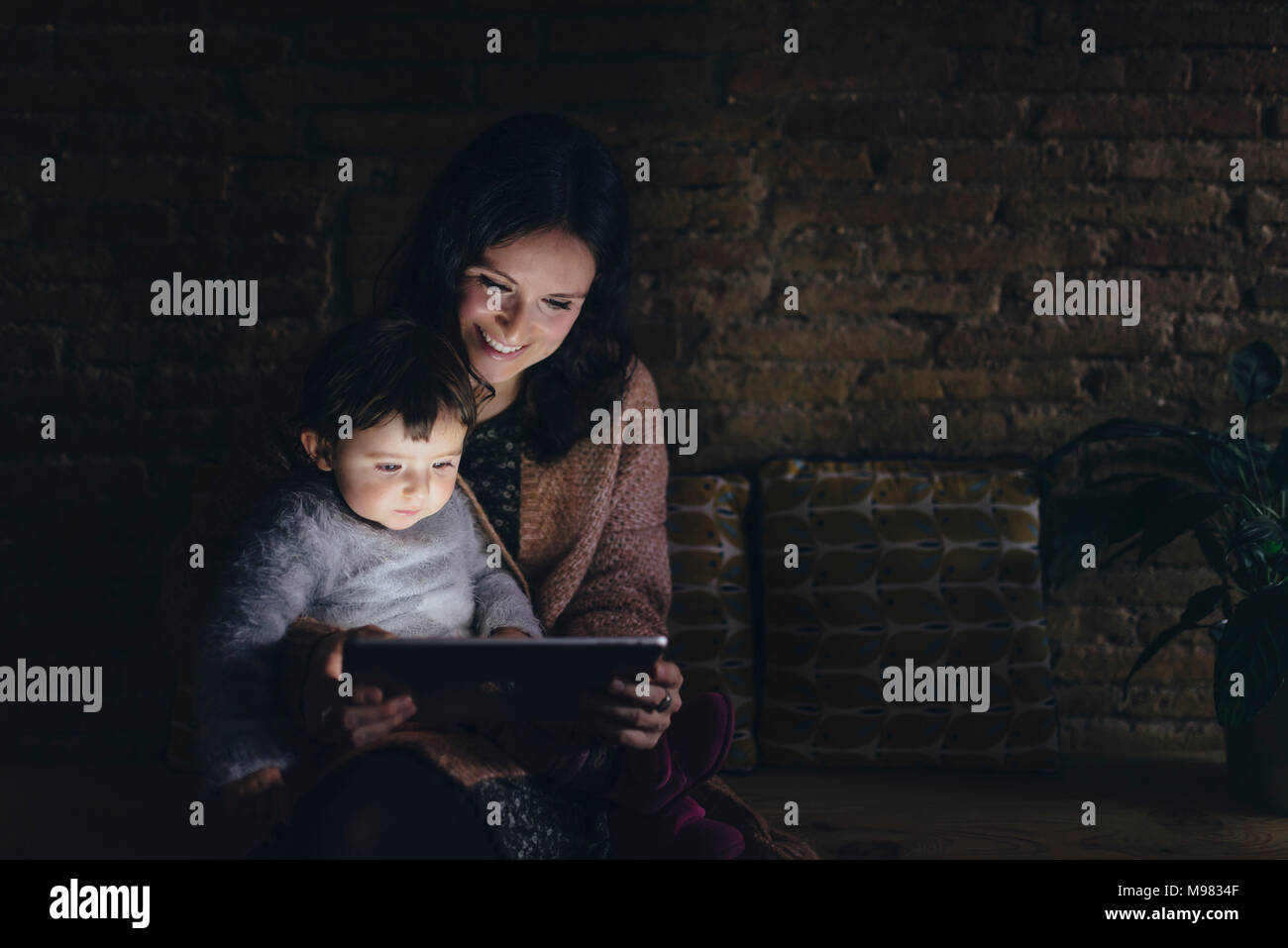 Mutter und Tochter mit digitalen Tablette zu Hause in der Dunkelheit Stockfoto