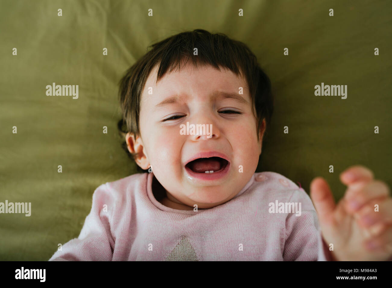 Porträt von weinenden Babymädchen auf Bett liegend Stockfoto
