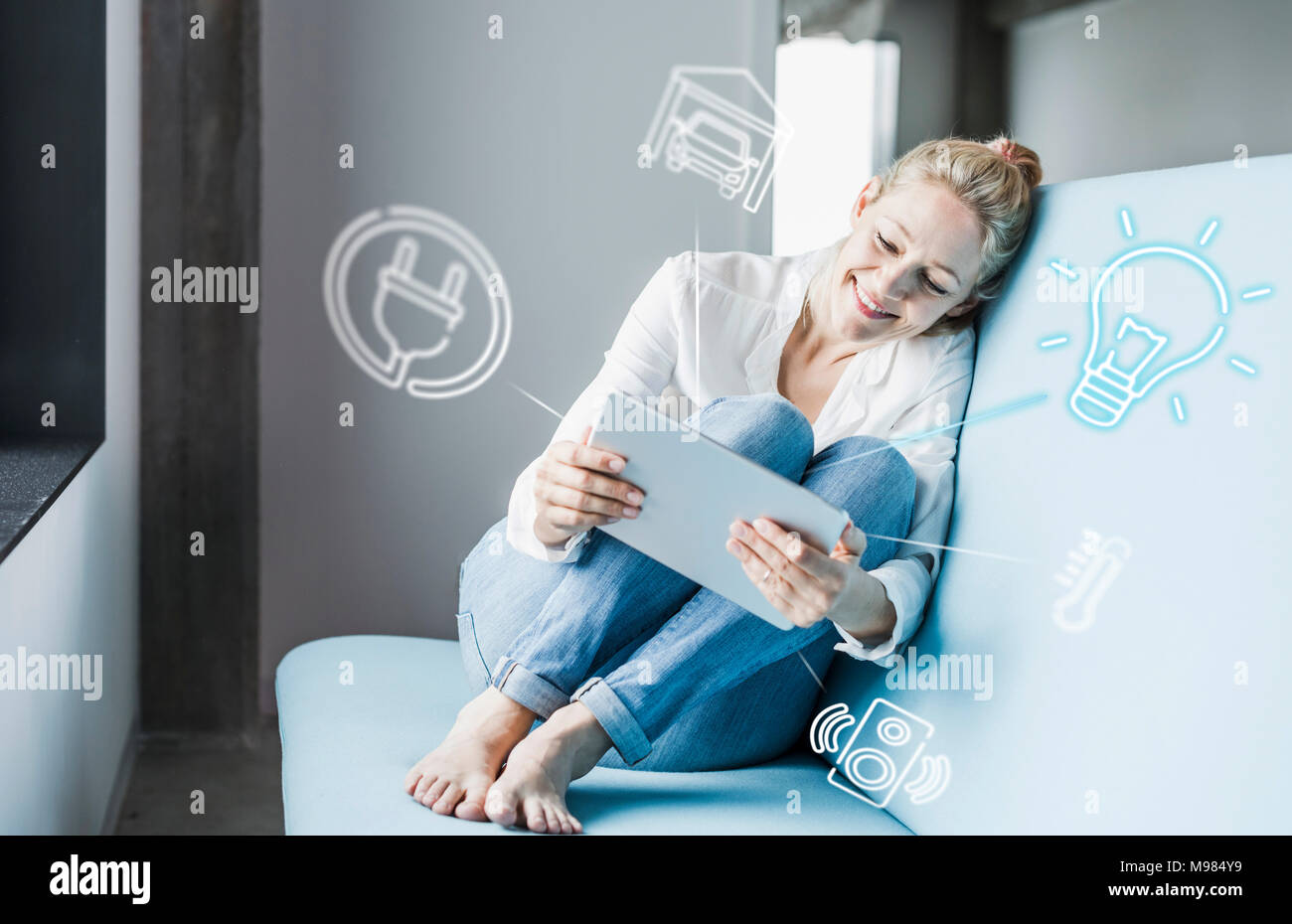 Frau sitzt im Büro, mit digitalen Tablet auf remote-control seine Smart Home Stockfoto