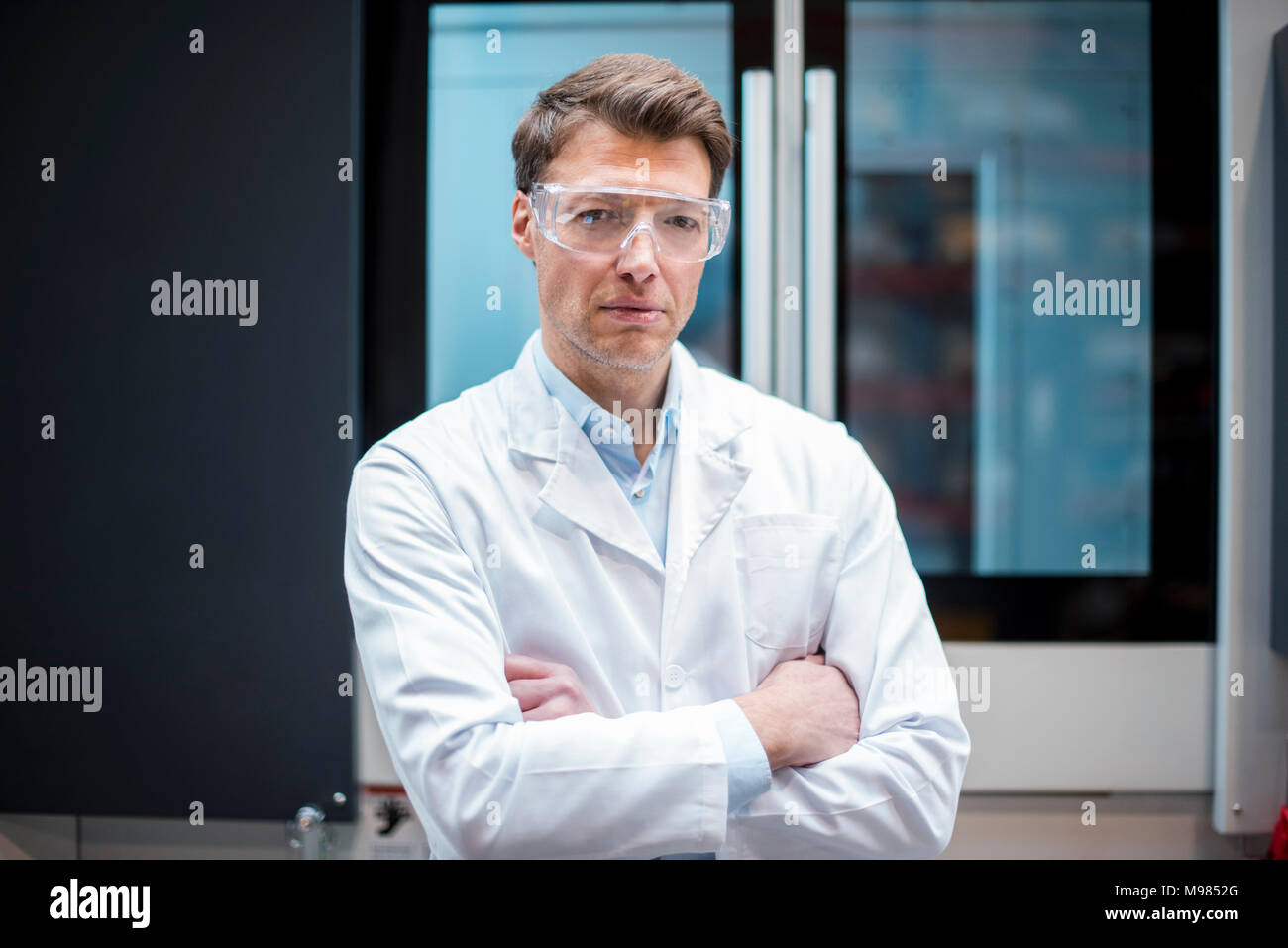 Porträt der Mann mit Laborkittel und Schutzbrille an Maschine Stockfoto