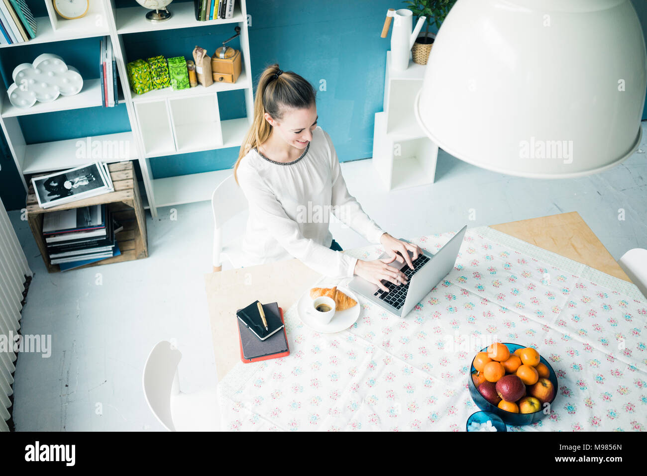 Lächelnde Frau am Laptop zu Hause arbeiten Stockfoto