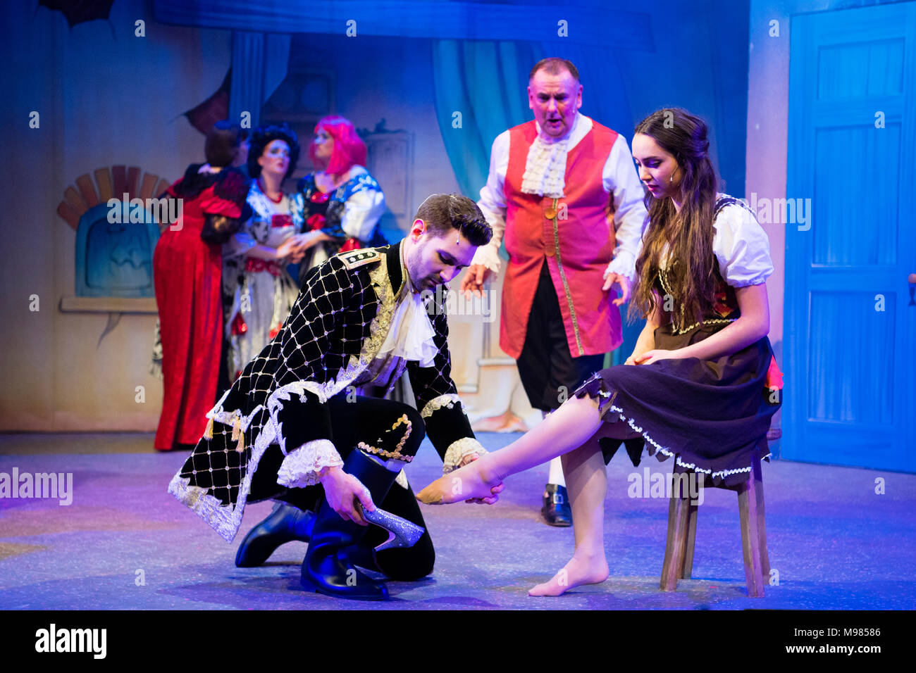 Prince Charming, den glass slipper auf Asche' Fuß: Schauspieler im Kostüm auf der Bühne in einem Laienhaften dramatische Unternehmen Produktion der klassischen Pantomime Aschenputtel, in Aberystwyth Arts Centre, 2018, UK Stockfoto