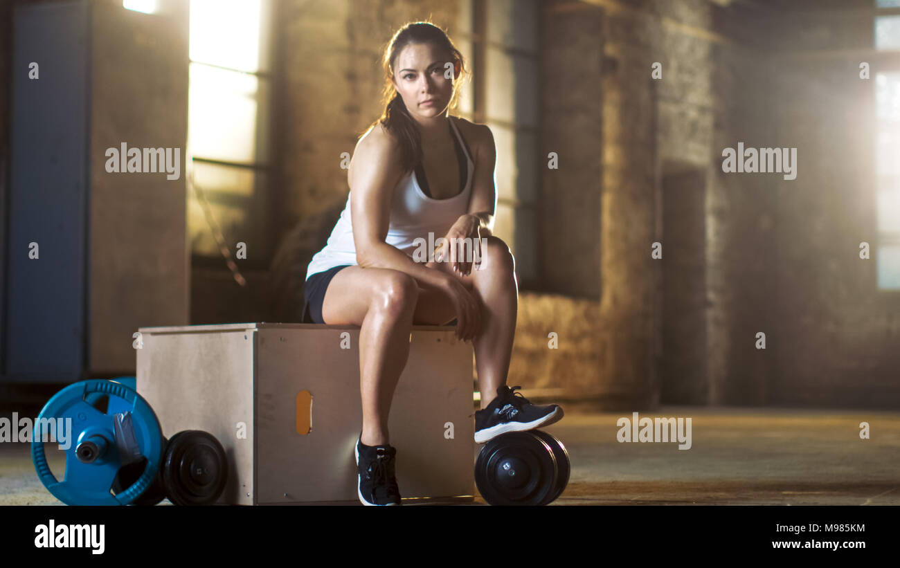 Schöne athletische Frau nutzt Smartphone für die Verfolgung ihrer intensiven Cross Fitness Bodybuilding Übung Programm an Ihrem bevorzugten Fitnessraum. Stockfoto