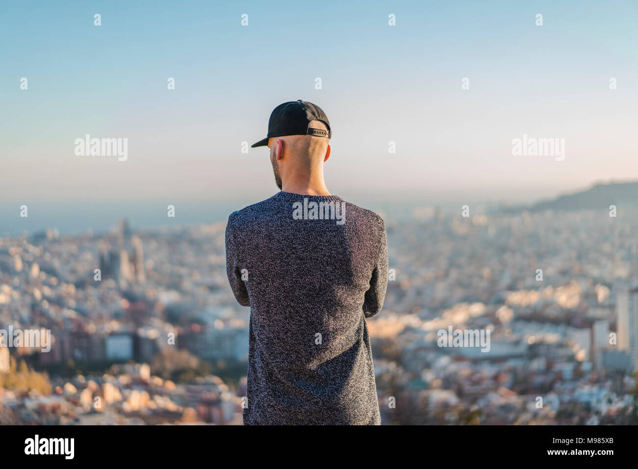 Spanien, Barcelona, jungen Mann, der auf einem Hügel mit Blick auf die Stadt Stockfoto