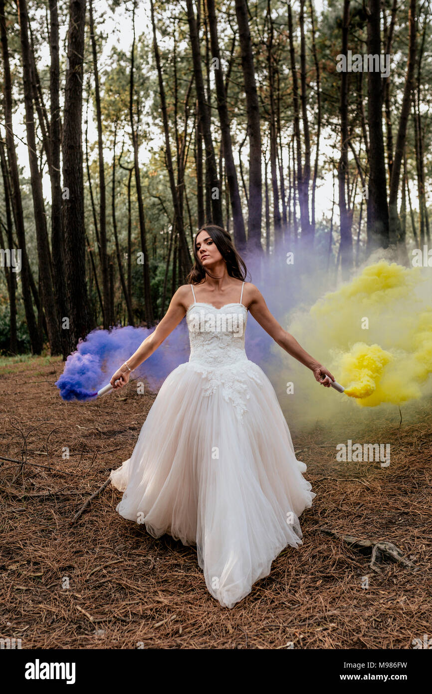 Frau mit einem Hochzeitskleid Kleid in Wald holding Rauch Fackeln  Stockfotografie - Alamy