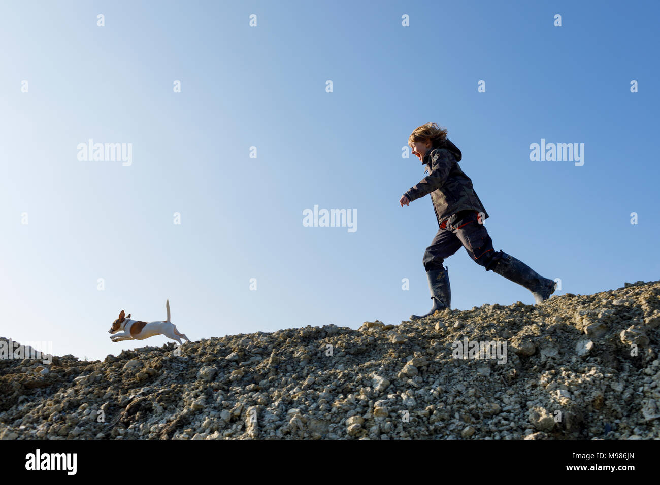 Glückliche junge mit Hund unter blauen Himmel Stockfoto