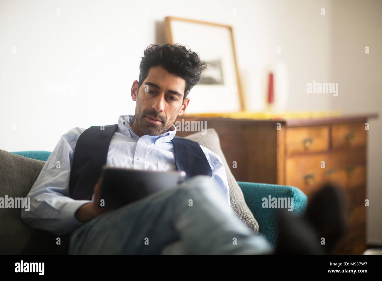 Porträt der Mann entspannt auf der Couch zu Hause sitzen mit Tablet Stockfoto
