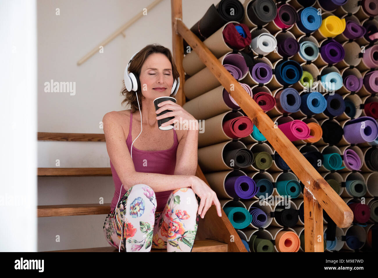 Reife Frau entspannt Musik hören neben Auswahl an Yogamatten Stockfoto