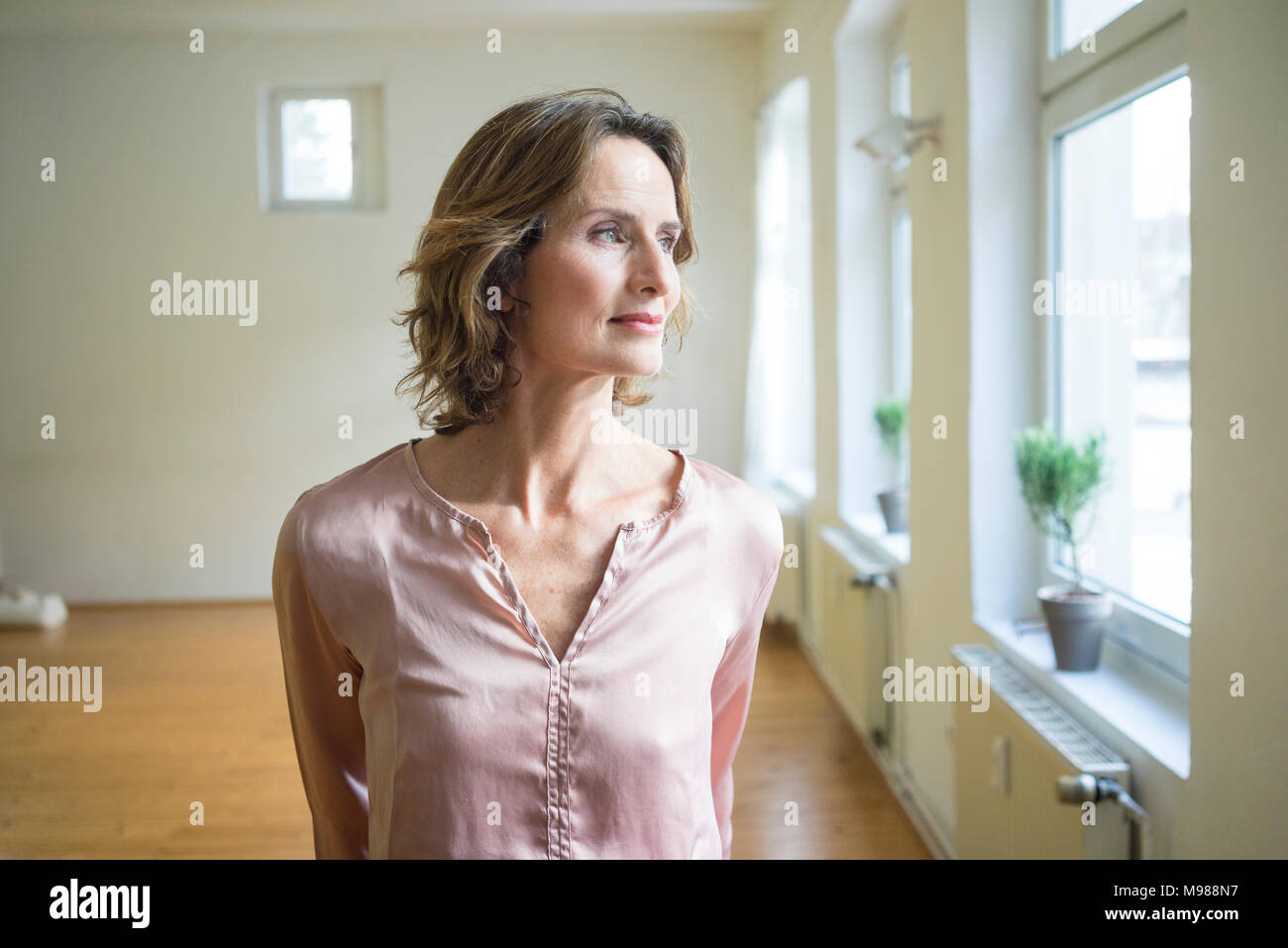 Nachdenklich, reife Frau im leeren Zimmer Stockfoto