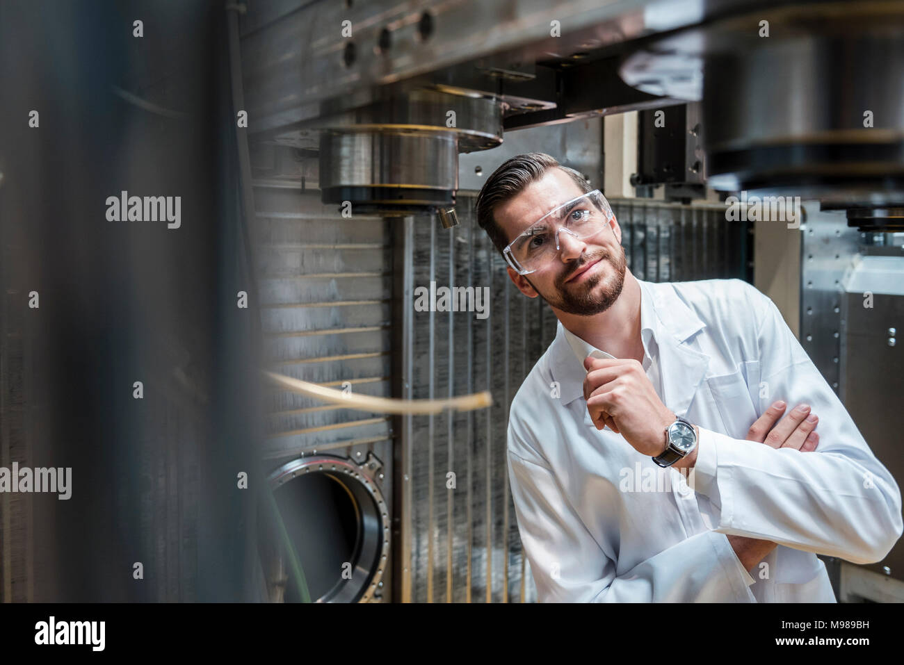 Mann mit Laborkittel und Schutzbrille an Maschine Stockfoto