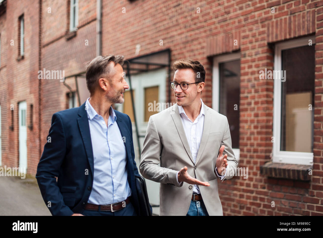 Zwei Geschäftsleute sprechen bei Ziegelgebäude Stockfoto