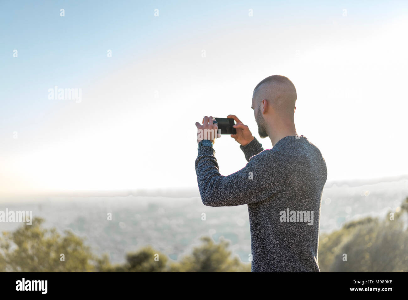 Junger Mann auf einem Hügel unter Handy Bild Stockfoto