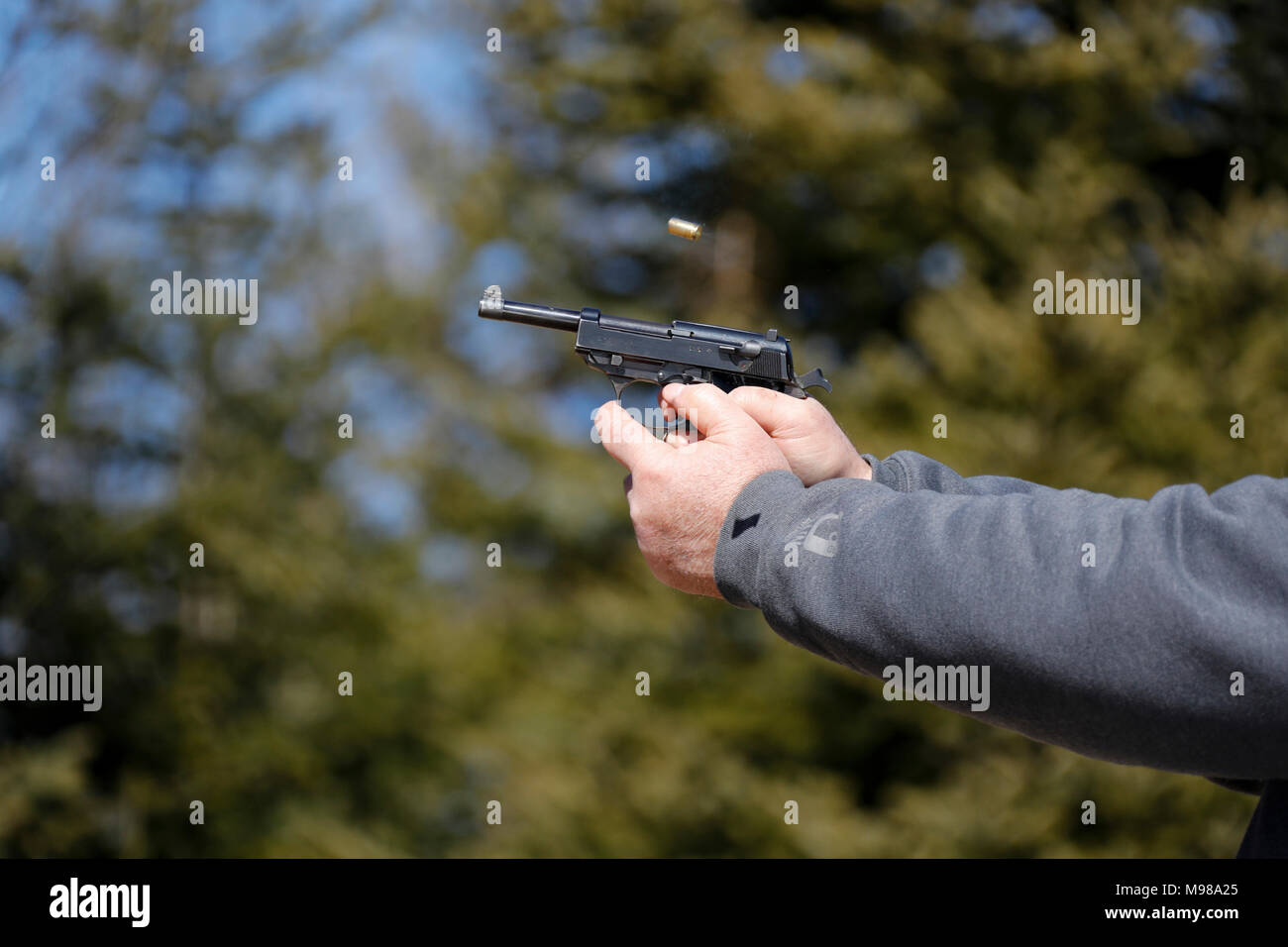 Nahaufnahme einer Pistole abgefeuert wurde und die ausgeworfene Shell wird in der Luft sichtbar. Stockfoto