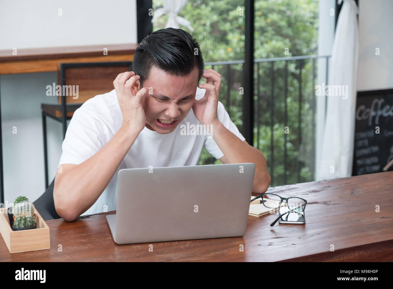 Asien legerer Mann Abdeckung Gesicht mit der Hand von der Arbeit umgekippt Vor laptop computer im Coffee Shop, Stress Emotionen Konzept, Arbeiten im Büro, arbeiten in hom Stockfoto