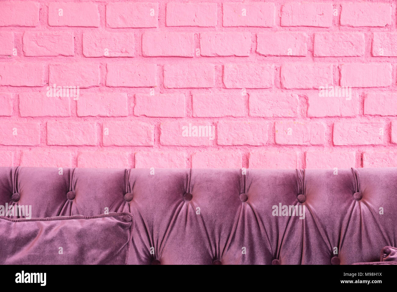 Purple luxus Sofa bei Pastell rosa Anstrich auf Mauer, Platz zum Hinzufügen von Ihrem Design oder benutzen Sie sie als Hintergrund für Ihr Produkt werben lassen. Stockfoto