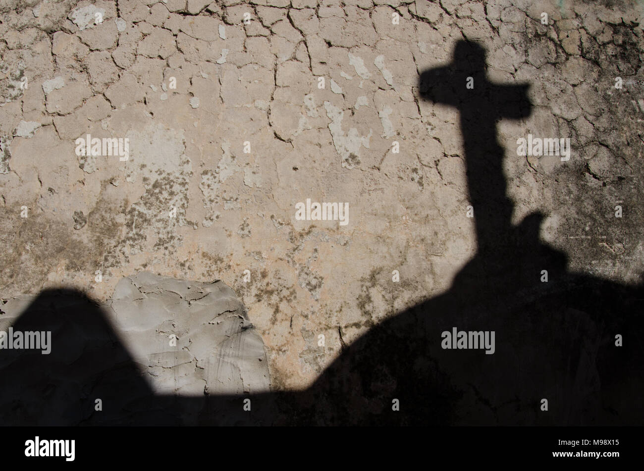 Schatten des religiösen Kreuz auf Risse im Lehm Mauer. Religiöse Symbolik Kruzifix. Stockfoto