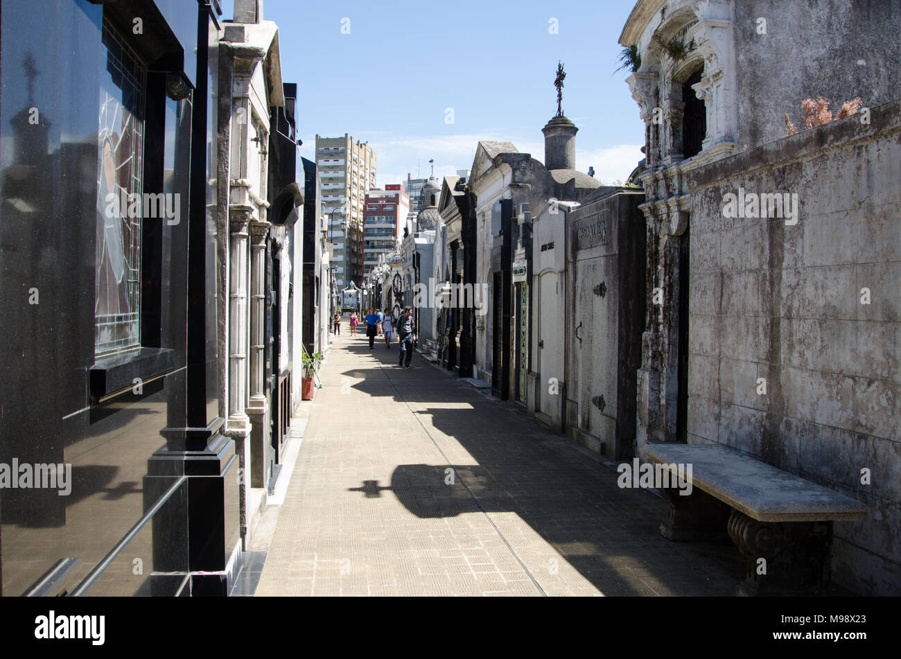 Menschen gehen zwischen den Mausoleen in alten historischen Friedhof, mit Stadt Kulisse - am Friedhof von Recoleta, Buenos Aires. Stockfoto