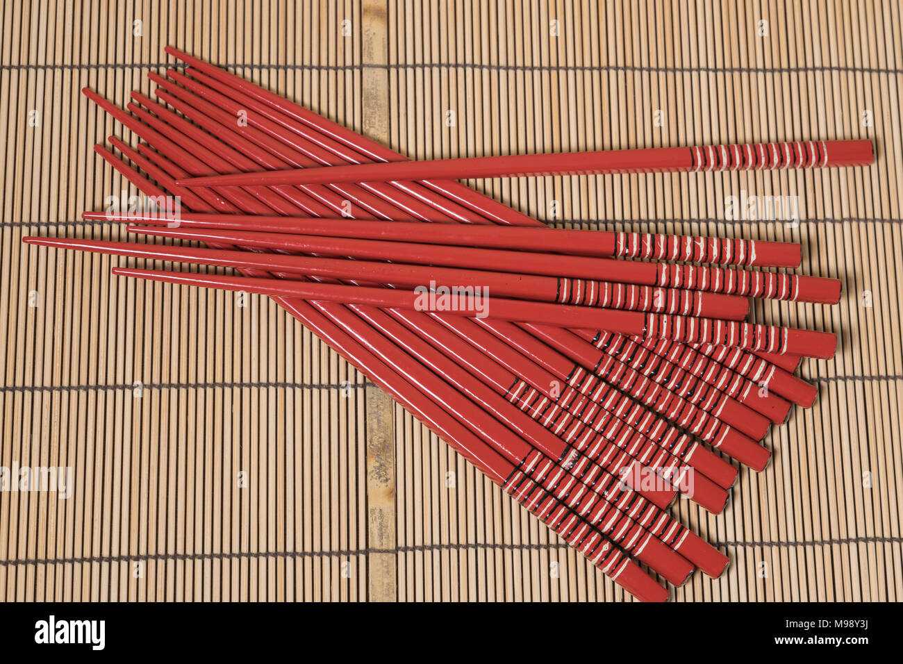 Rot lackierten Stäbchen auf einem Bambus Matte Stockfoto