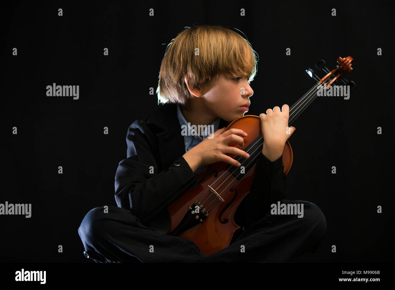 Kind spielen Geige, schwarzer Hintergrund, melancholisch, traurig,  nachdenklich, konzentriert Stockfotografie - Alamy
