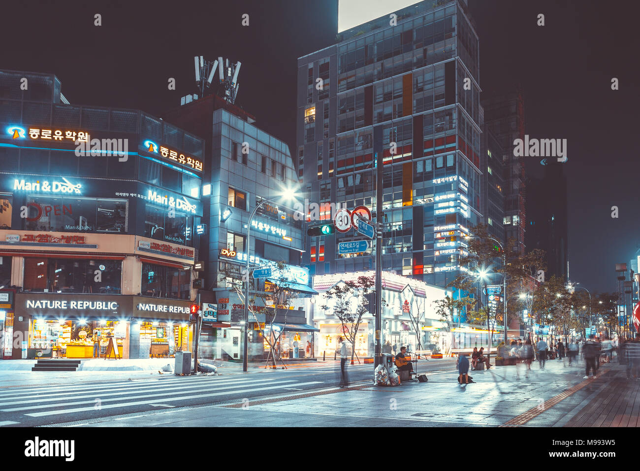 SEOUL, Südkorea - 12. AUGUST 2015: Junge Menschen zu Fuß an einer stark befahrenen Hauptstraße von sinchon Bezirk bei Nacht - Seoul, Südkorea Stockfoto