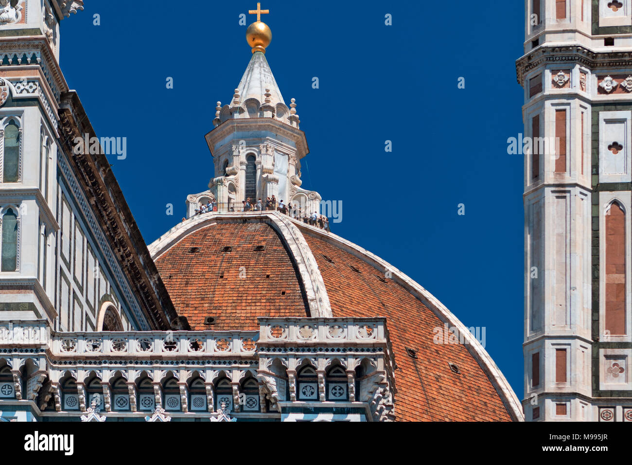 Der Dom von Florenz, die Kathedrale von Santa Maria Del Fiore, mit Touristen auf dem Balkon mit dekorativen Stein Architektur gerahmt und einem tiefblauen Himmel Stockfoto