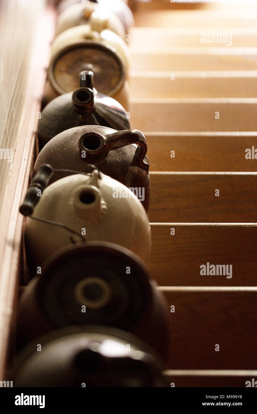 Eine Reihe von antiken Keramik Krüge aufgereiht auf einer Treppe, mit der Sonne ein ombre Wirkung auf die hölzernen Stufen. Stockfoto