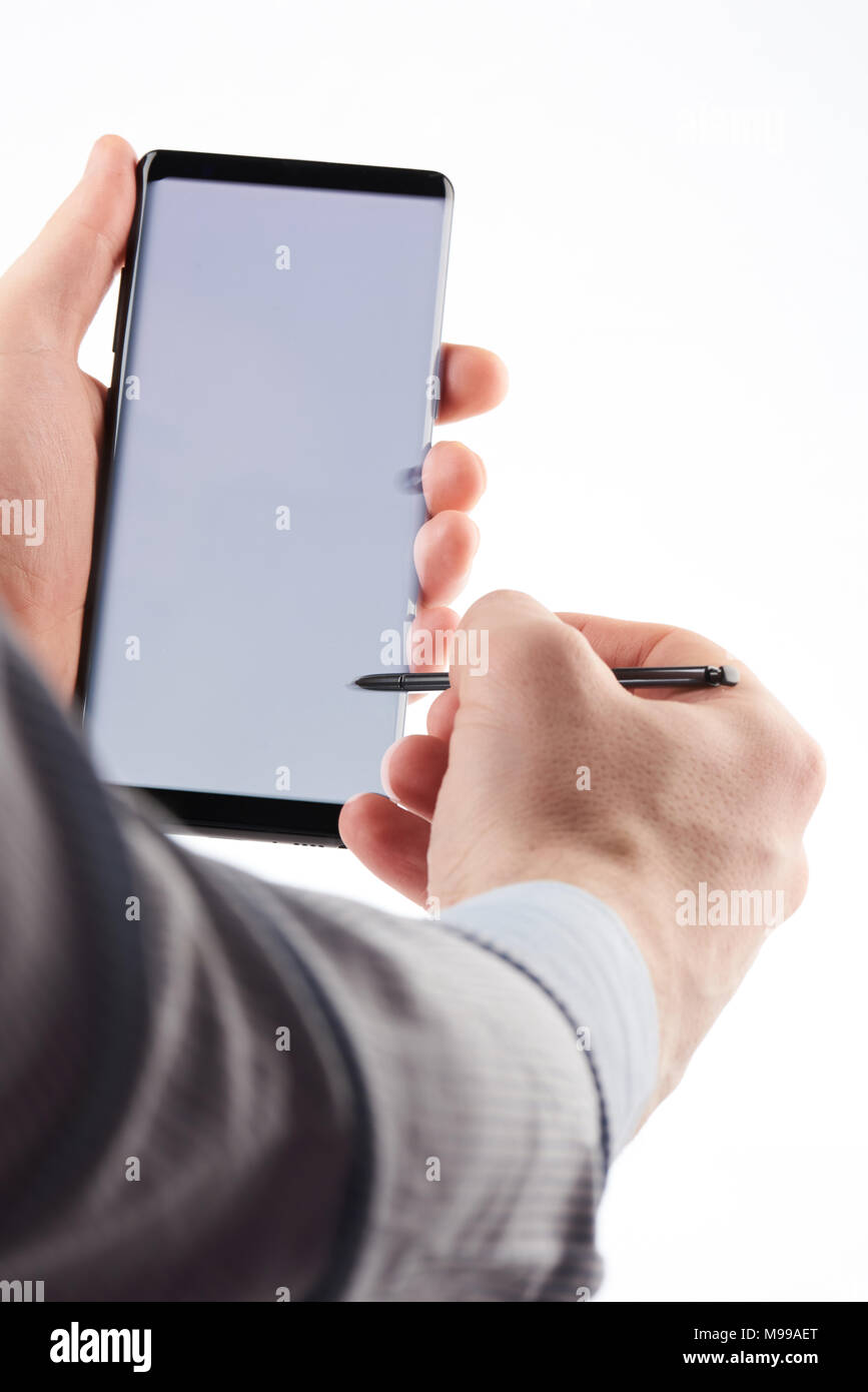 Mit Smartphone mit Stift tippen Sie auf weißem Hintergrund Stockfoto