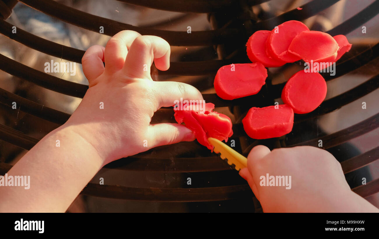 Baby Hände schneiden Plastilin - feinmotorische Fähigkeiten entwickeln, Geschicklichkeit - pov oben anzeigen Stockfoto