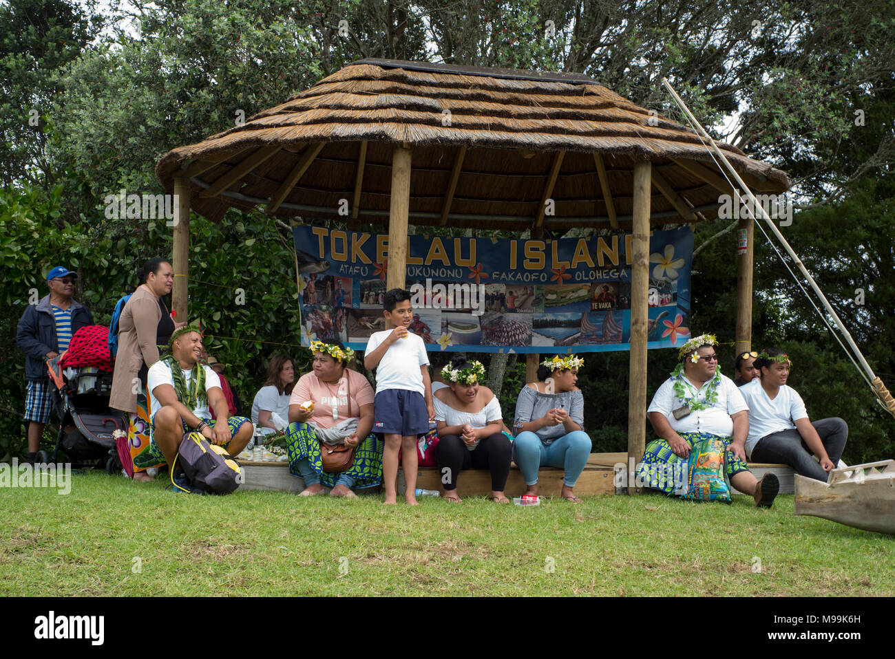 Eine Gruppe von Menschen, die Zuflucht in einer Fale am Tokelau Island Village Pavillon, Pasifica Festival, Auckland, Neuseeland Stockfoto