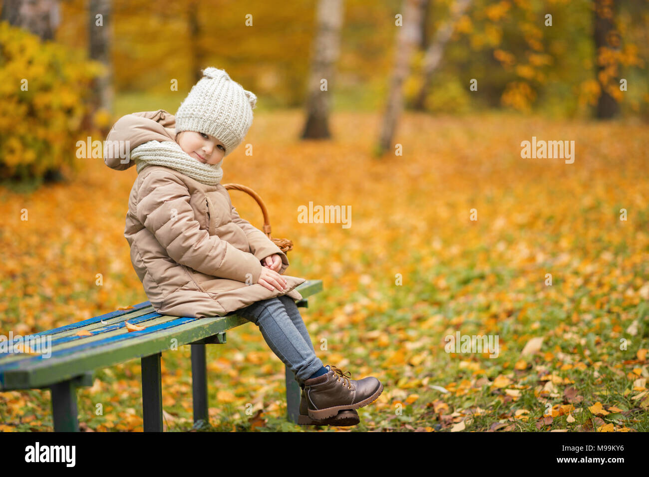 Mädchen sitzt auf einer Parkbank im Herbst Stockfoto