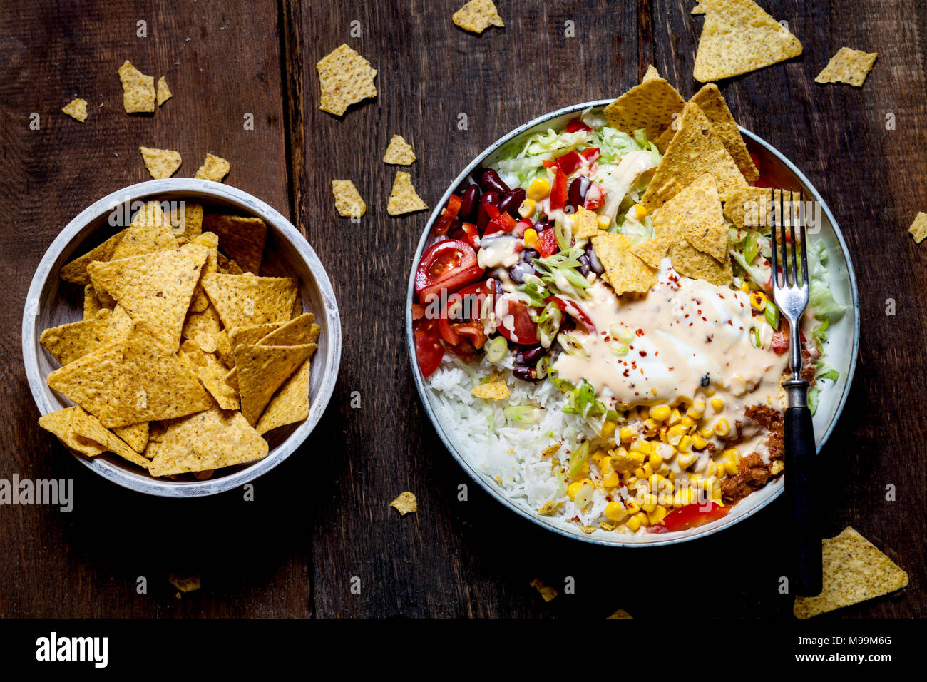 Taco Salat Schüssel mit Reis, Mais, Chili con Carne, Bohnen, Eisbergsalat, saure Sahne, Nacho Chips, Tomaten Stockfoto