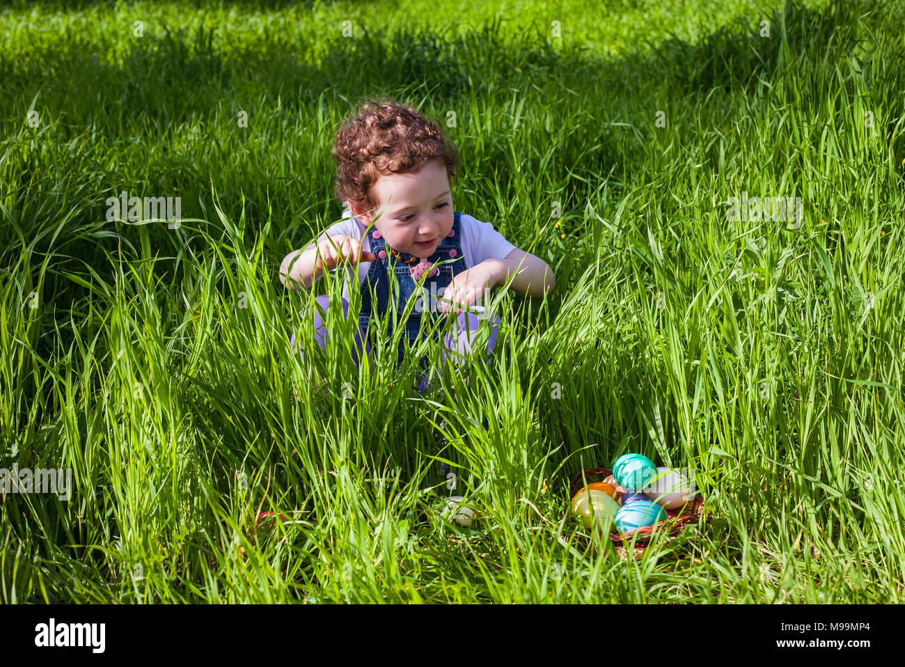 Niedliches kleinkind Mädchen auf der Suche nach Eier an Ostern Jagd Stockfoto