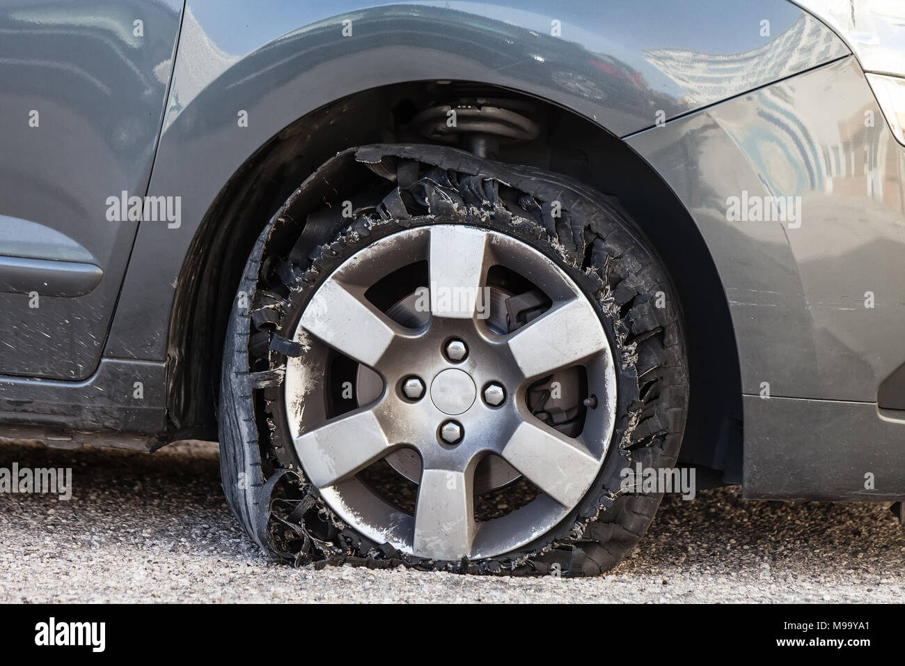 Sie zerstörte Reifen geblasen mit explodierte, geschreddert und beschädigte Gummi auf modernem SUV Automobil. Flache flache Reifen auf einer Leichtmetallfelge, riss öffnen Stockfoto