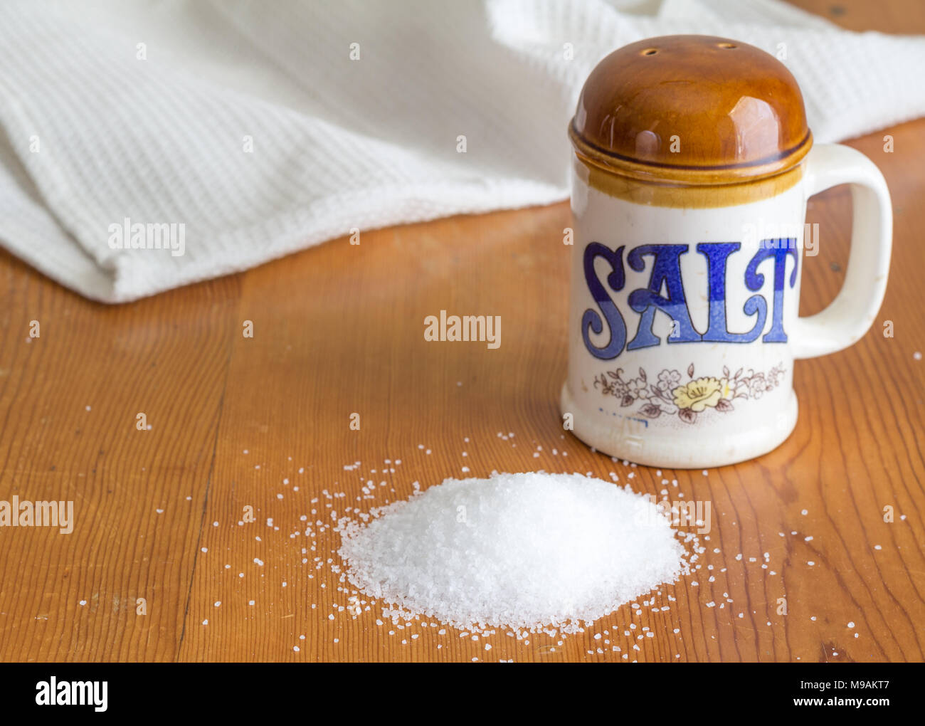 Keramik retro Salt Shaker auf rustikalen Küche aus Holz Tisch mit Haufen von Salzkristallen - Küche Hintergrund mit Platz für Text Stockfoto