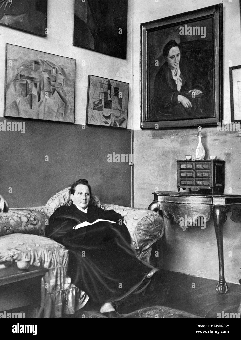 Gertrude Stein (1874-1946). Portrait der amerikanische Schriftsteller und Dramatiker sitzen in ihrer Pariser Studio mit einem Gemälde von ihr von Picasso an der Wand, c 1930. Stockfoto
