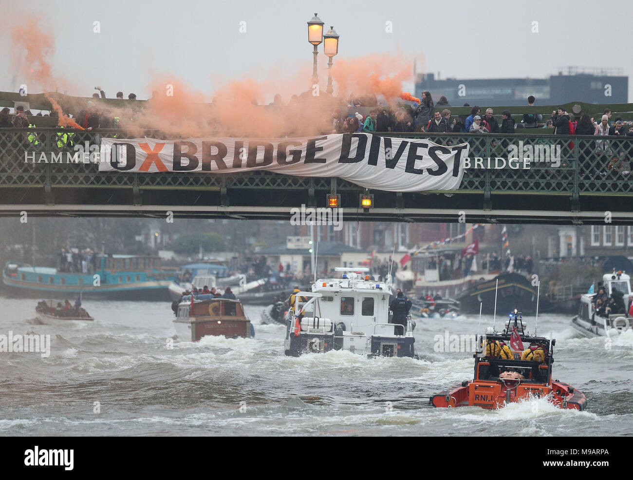 Umweltaktivisten aus Oxford und Cambridge protestieren während des Men Boat Race auf der Hammersmith Bridge in London und fordern, dass 'beide Universitäten sich zu einer vollständigen Veräußerung fossiler Brennstoffe verpflichten'. Stockfoto